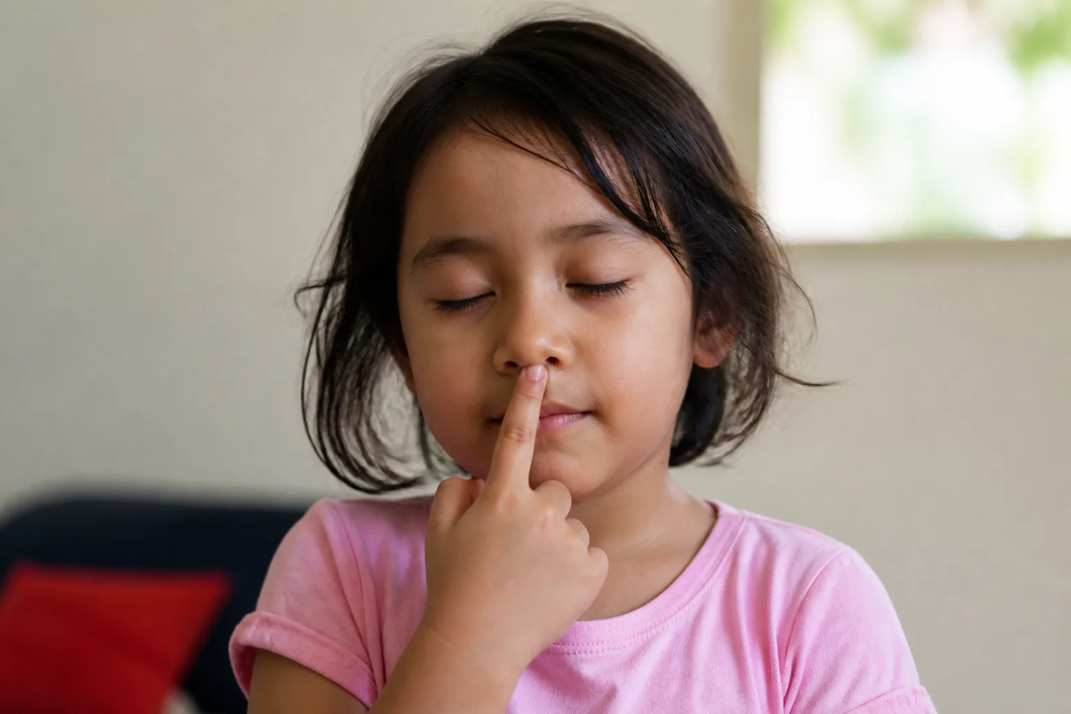 Niña tocándose la nariz con los ojos cerrados